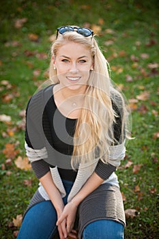 BEAUTIFUL YOUNG WOMAN RESTS IN PARK ON A WARM AUTUMN DAY