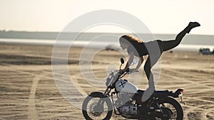 Beautiful young woman riding on an old motorcycle and doing a trick. in the desert at sunset or sunrise. Female biker. Stabilized