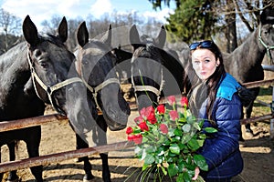 Beautiful young woman with roses and black horses