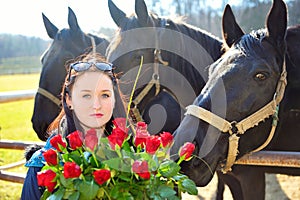 Beautiful young woman with roses and black horses