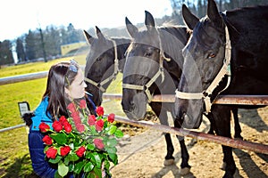 Beautiful young woman with roses and black horses