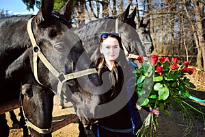 Beautiful young woman with roses and black horses