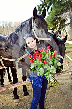 Beautiful young woman with roses and black horses