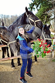 Beautiful young woman with roses and black horses