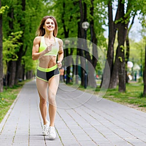 Beautiful young woman running in the green park.