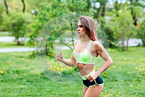 Beautiful young woman running in the green summer park.