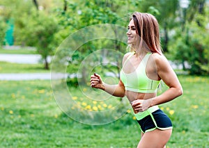 Beautiful young woman running in the green summer park.