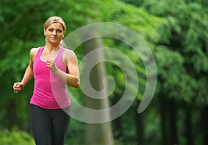 Beautiful young woman running in the park in sportswear