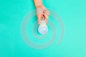 Beautiful young woman`s hands holding bulb   on pastel  background