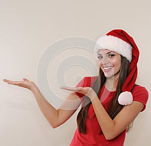Beautiful young woman in Santa hat advertise and show an ampty p