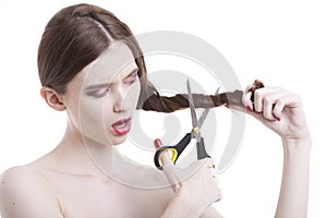 Beautiful young woman with scissors cutting her hair over white background