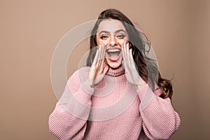 Beautiful young woman scream in studio over a brown background