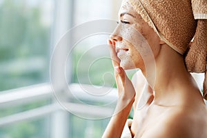 Beautiful young woman with scrub mask in spa salon