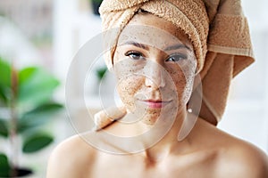 Beautiful young woman with scrub mask in spa salon