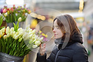 Beautiful young woman selecting fresh tulips at famous Amsterdam flower market Bloemenmarkt