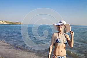 Beautiful young woman in sexy bikini standing at sea beach