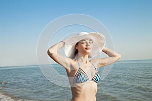 Beautiful young woman in sexy bikini standing at sea beach