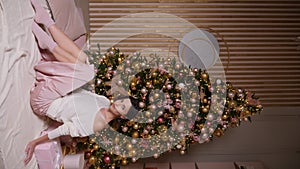 beautiful young woman in a short dress stands at the Christmas tree in the studio. a model poses for the camera at a