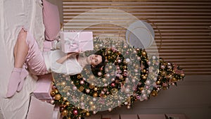 beautiful young woman in a short dress stands at the Christmas tree in the studio. a model poses for the camera at a