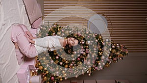 beautiful young woman in a short dress stands at the Christmas tree in the studio. a model poses for the camera at a