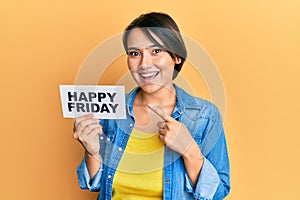 Beautiful young woman with short hair holding happy friday message paper smiling happy pointing with hand and finger