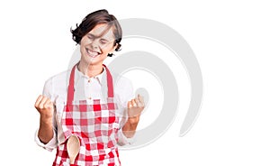Beautiful young woman with short hair wearing professional cook apron very happy and excited doing winner gesture with arms