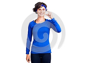 Beautiful young woman with short hair wearing training workout clothes smiling and confident gesturing with hand doing small size