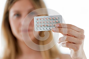 Beautiful young woman showing contraceptive pills over white background.