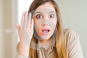Beautiful young woman showing engagement ring on hand scared in shock with a surprise face, afraid and excited with fear
