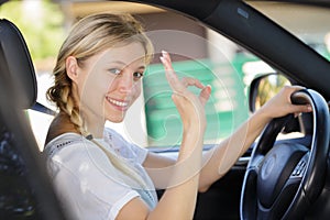 beautiful young woman showing ok sign in car