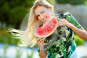 Beautiful young woman showing a slice of watermelon. She is caucasian. Summer and lifestyle concepts.