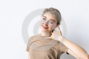 beautiful young woman shows gesture call me back on white background