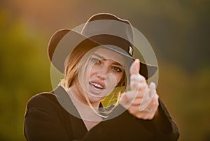 Beautiful young woman simulate shooting with and fingers. Cowgirl in cowboy hat with finger gun. Fashion and beauty. photo
