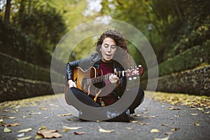 Beautiful young woman singing and playing guitar.