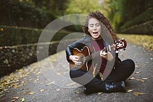 Beautiful young woman singing and playing guitar.