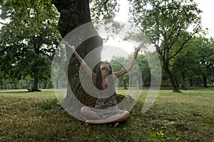 Beautiful young woman sit under a tree