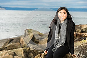 Beautiful Young Woman Sitting on Beach Driftwood