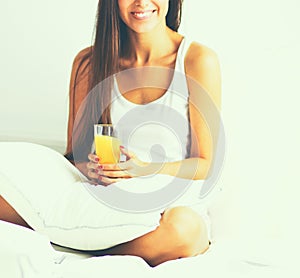 Beautiful young woman sitting in bed and having breakfast