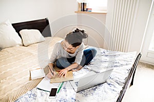 Beautiful young woman sitting on bed, working. Home office.