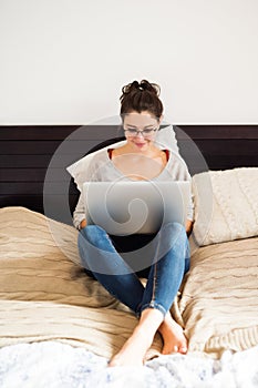 Beautiful young woman sitting on bed, working. Home office.