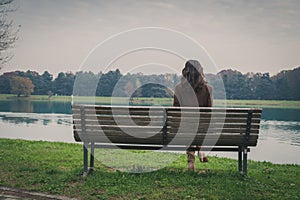 Beautiful young woman sitting on a bench in a city park