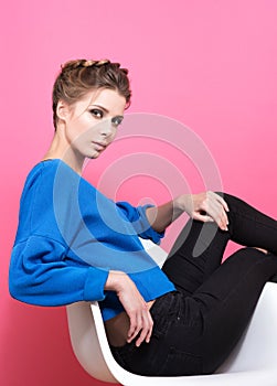 Beautiful young woman sitting on a chair. Stylish appearance