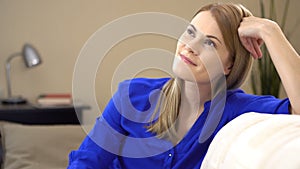 Beautiful young woman sitting on a couch and dreaming of something good and positive. Enjoying life.