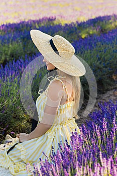 Beautiful young woman sitting in the field full of lavender flowers photo
