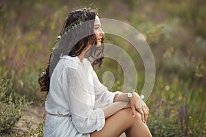 Beautiful young woman sitting in a wheat field in the summer sunset. Beauty and summer concept