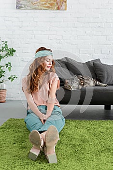 beautiful young woman sitting on floor near her tabby cat