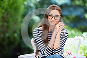 Beautiful young woman sitting at home in the garden and smiling