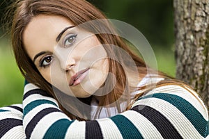 Beautiful Young Woman Sitting Leaning Against Tree