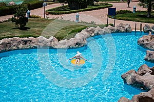 Beautiful young woman sitting on life preserver in pool