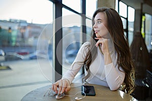 Beautiful young woman sitting and looking out the window in a cafe restaurant